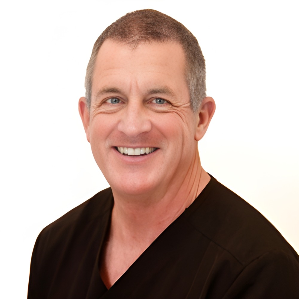 Dr. John Love smiling, in black scrubs against a white background