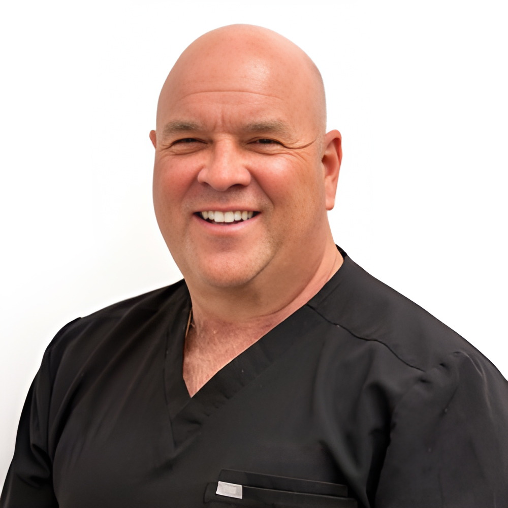 Dr. Lou Orosz smiling, in black scrubs against a white background