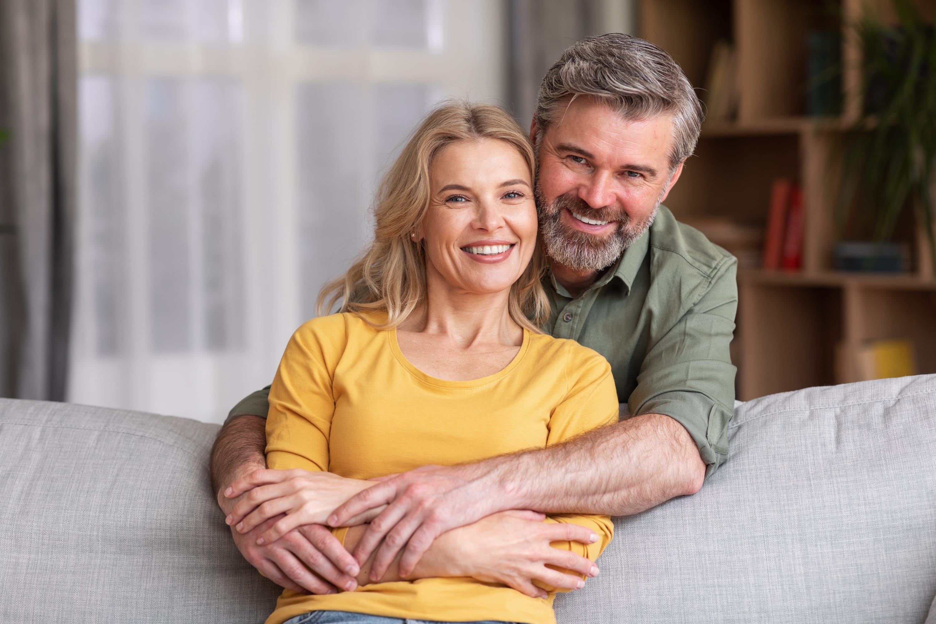 Smiling couple sitting close together on a sofa at home